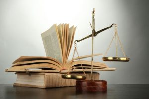 16467530 - gold scales of justice and books on grey background