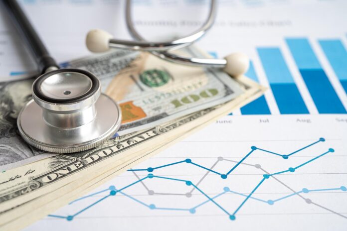 Stethoscope with US dollar banknotes on chart and graph paper, F investigación de enfermedades raras 2025